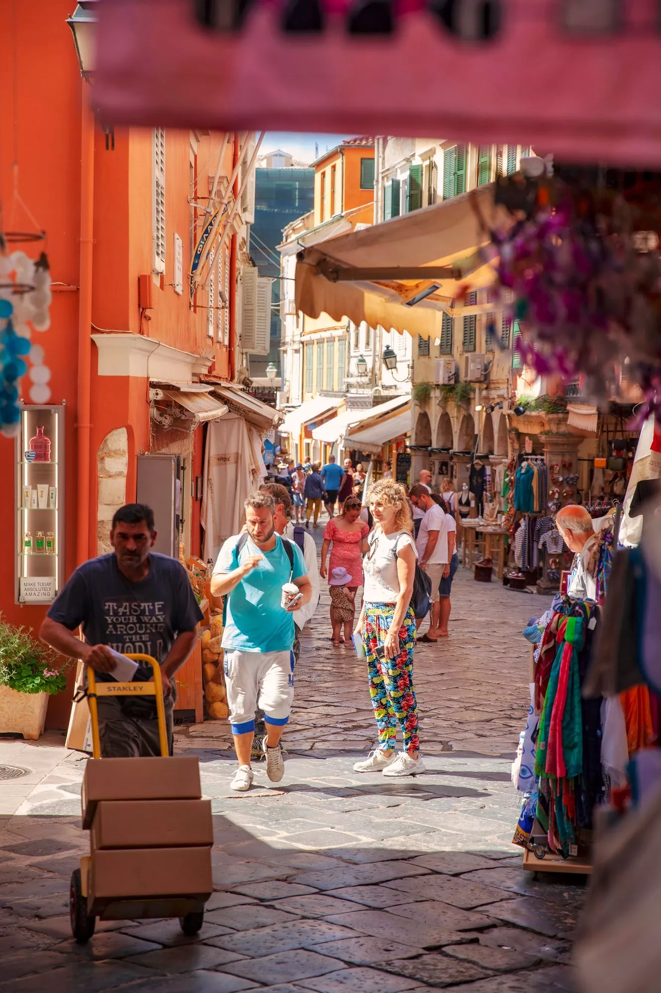 Korfu: Aamuvarhaisella vanhan kaupungin kaduilla puhaltelee vilvoittava tuuli. Matkailijalle tarjotaan kaikkea rihkamasta näppäriin käyttöesineisiin ja jalometallikoruihin. Mausteet, mausteseokset ja oliivista tehdyt tuotteet ovat suosittuja. © Marjo Tynkkynen