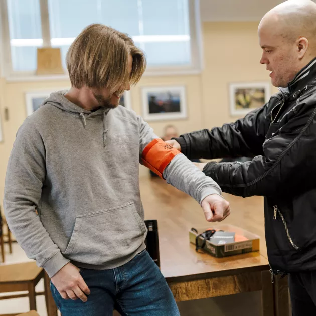 Jani Lindström laittaa lakkovahdin nauhaa Gunnar Sunessonin käsivarteen.