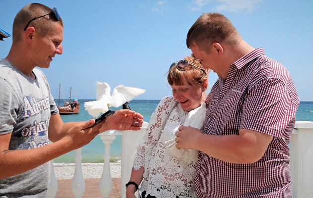 Sergei (vas.) elättää itsensä kuvaamalla turisteja kesyjen kyyhkyjen kanssa
