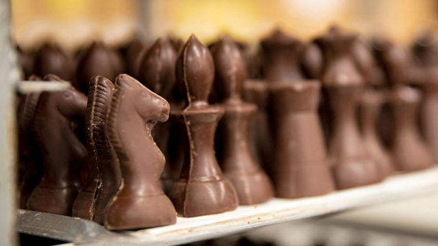 Suklaasta valmistetun shakkinappulan voi konkreettisesti syödä. Toisen pelaajan nappulat ovat tummaa suklaata, toisen valkosuklaata.