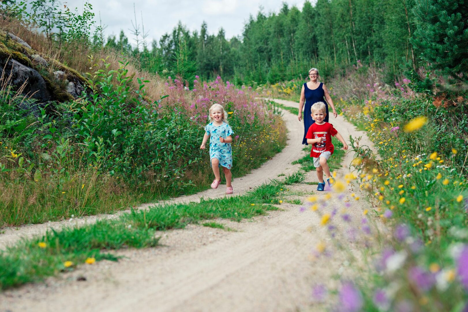 Mummolan tunnelmallisella mökkitiellä kelpaa Alinan ja Jimin kirmata. Mummi Annukka Toivola seuraa mukana. © Pihla Liukkonen