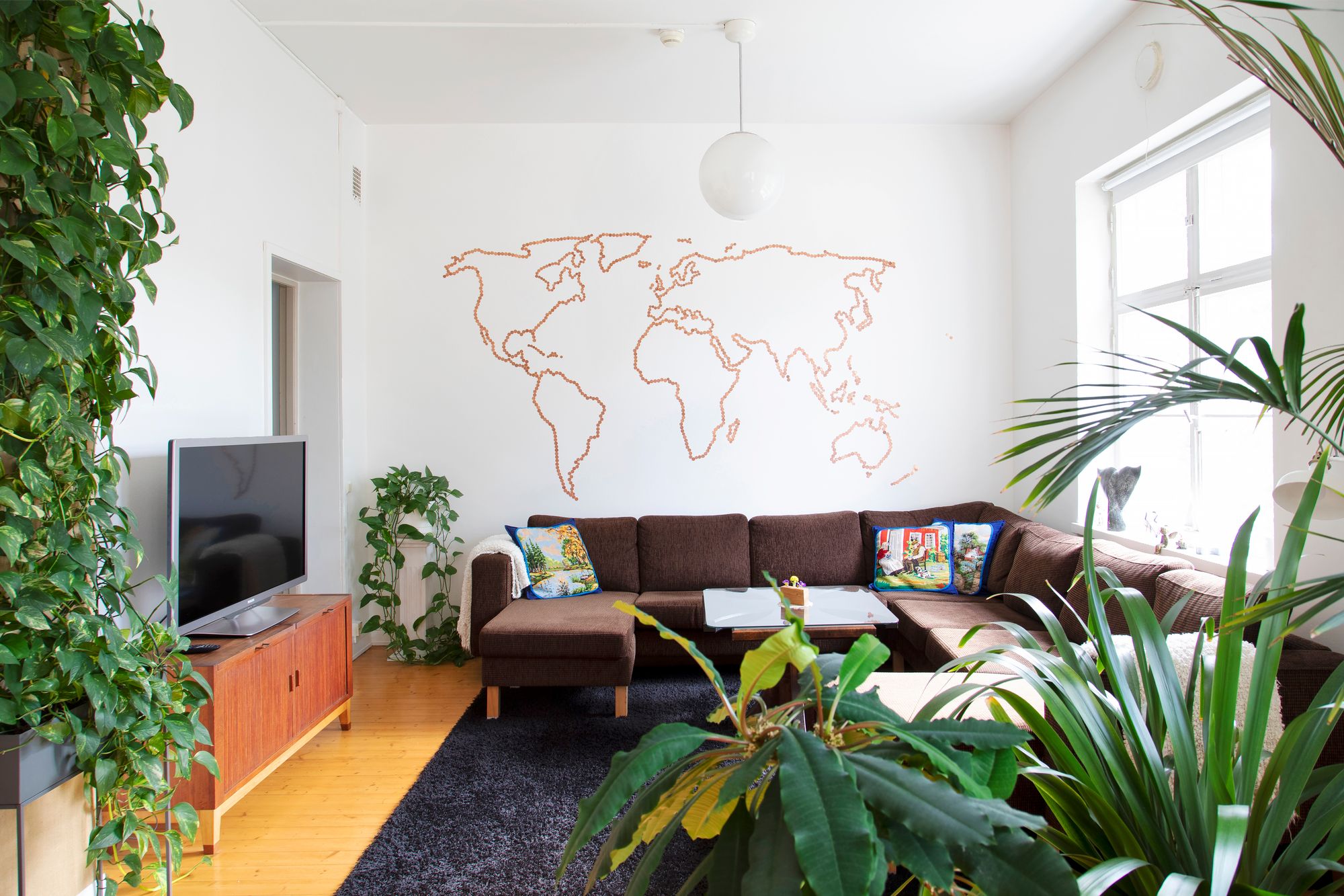 Olohuoneen seinää koristaa yhden, kahden ja viiden sentin kolikoista piirtyvä maailmankartta. © Suvi Elo