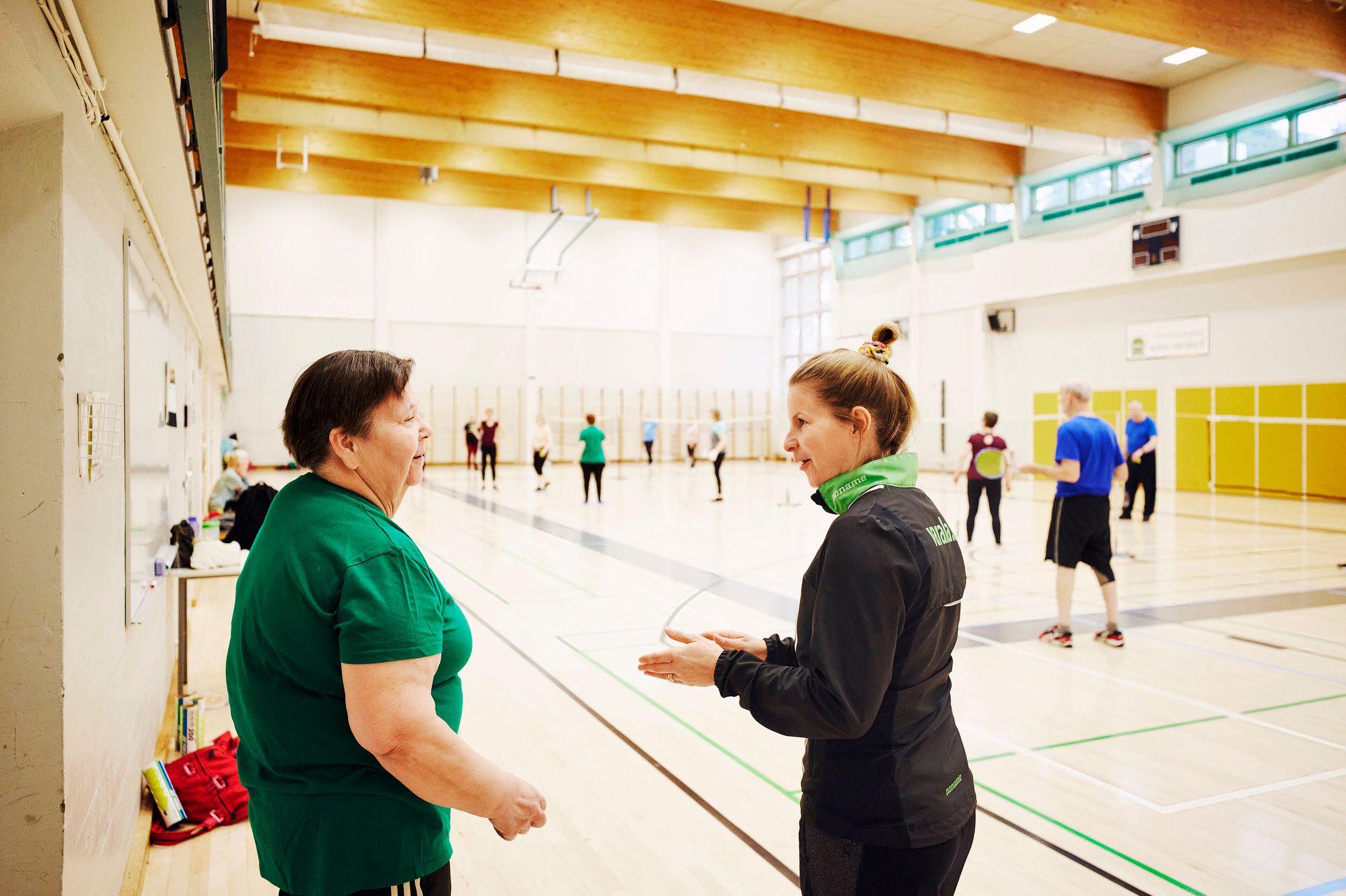 Liikunnan ja hyvinvoinnin asiantuntija Tupu Nordström (oik.) keskustelee Birgitta Svalan kanssa Elämäniloa-kurssilla arkiliikunnan tärkeydestä ennen sulkapallotuntia. 