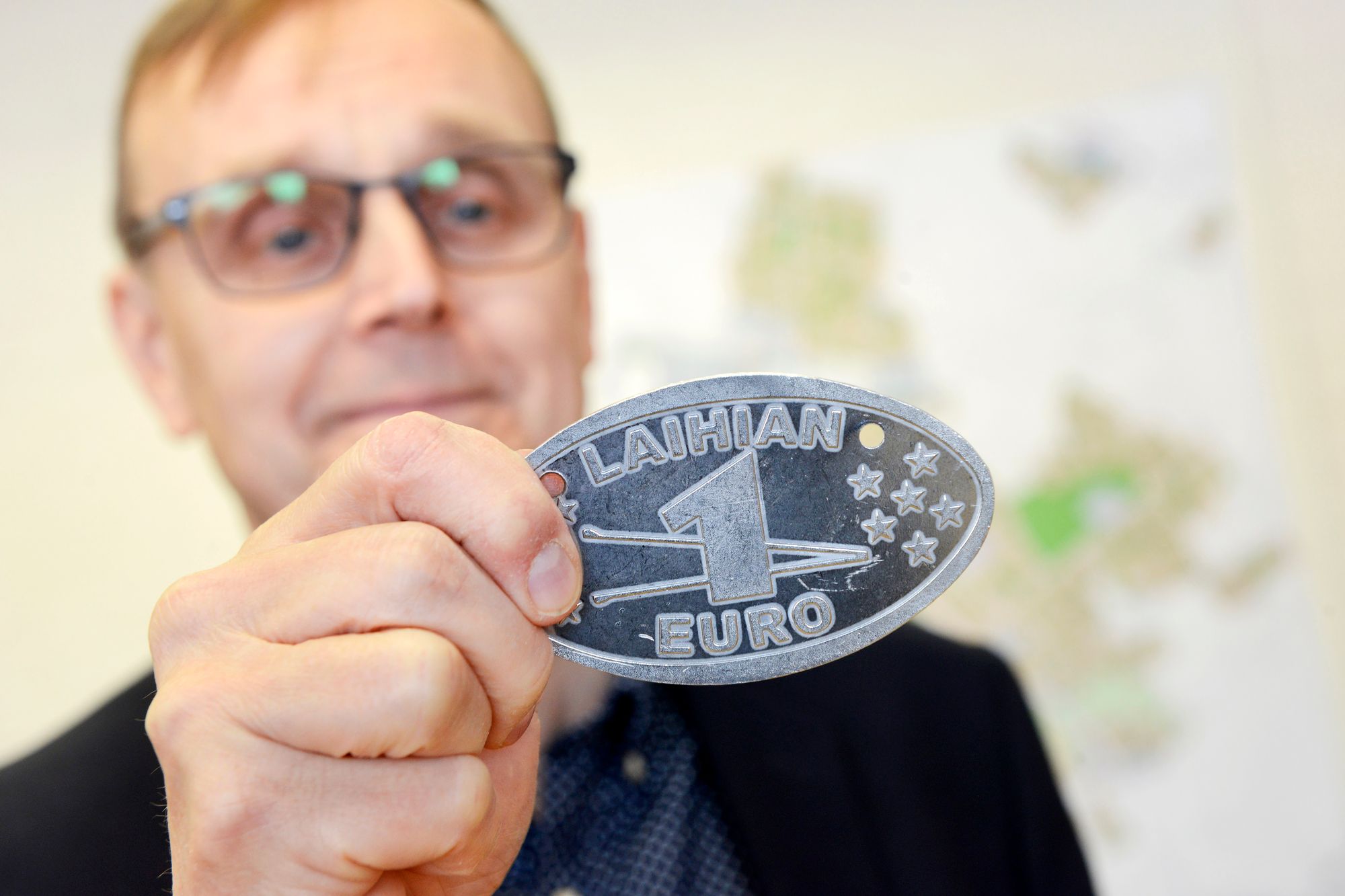 Juha Rikala esittelee Laihian euroa, jossa tulitikku on halkaistu. © Juha Harju