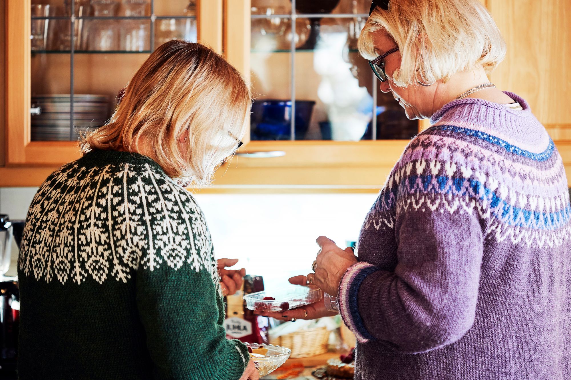 Tuula Puntala ja ­Minna Lähteenmäki kattavat lounaspöytään tuomiaan herkkuja, kotijuustoa ja täytekakkua. © Sara Pihlaja 