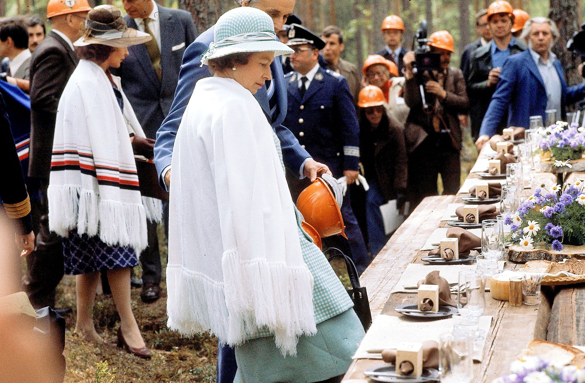 Englannin kuningatar Elisabet  II asettumassa lounaspöytään Haukanmaan metsätyömaalla Suomen vierailunsa aikana vuonna 1976. © Lehtikuva